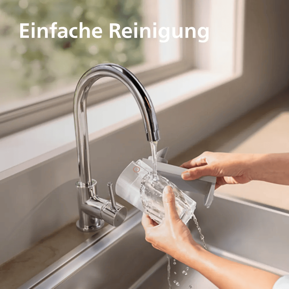 Person wäscht ein graues Haushaltsgerät unter dem Wasserhahn in einer Küchenspüle.