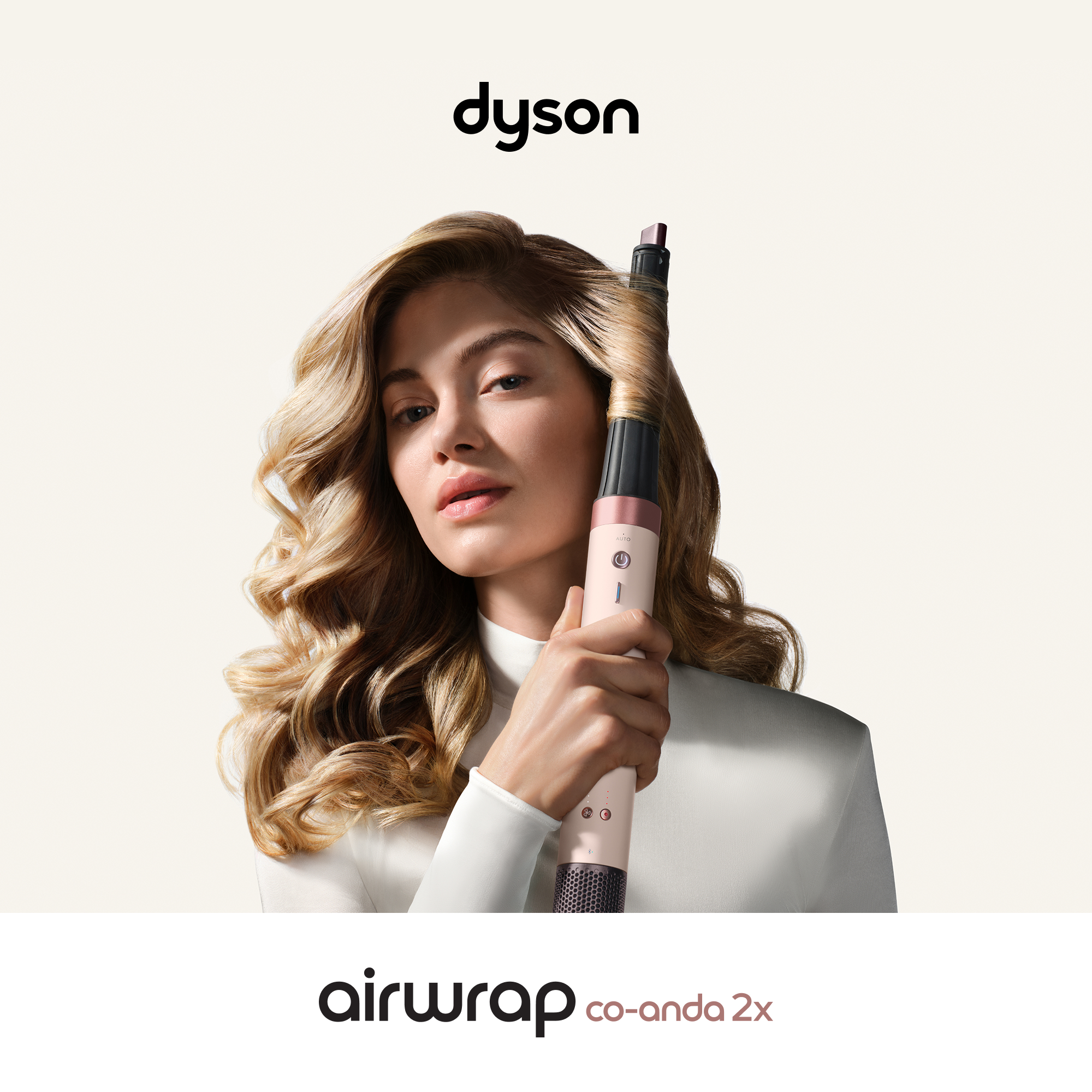 Mujer con cabello rubio ondulado sosteniendo un Dyson Airwrap.