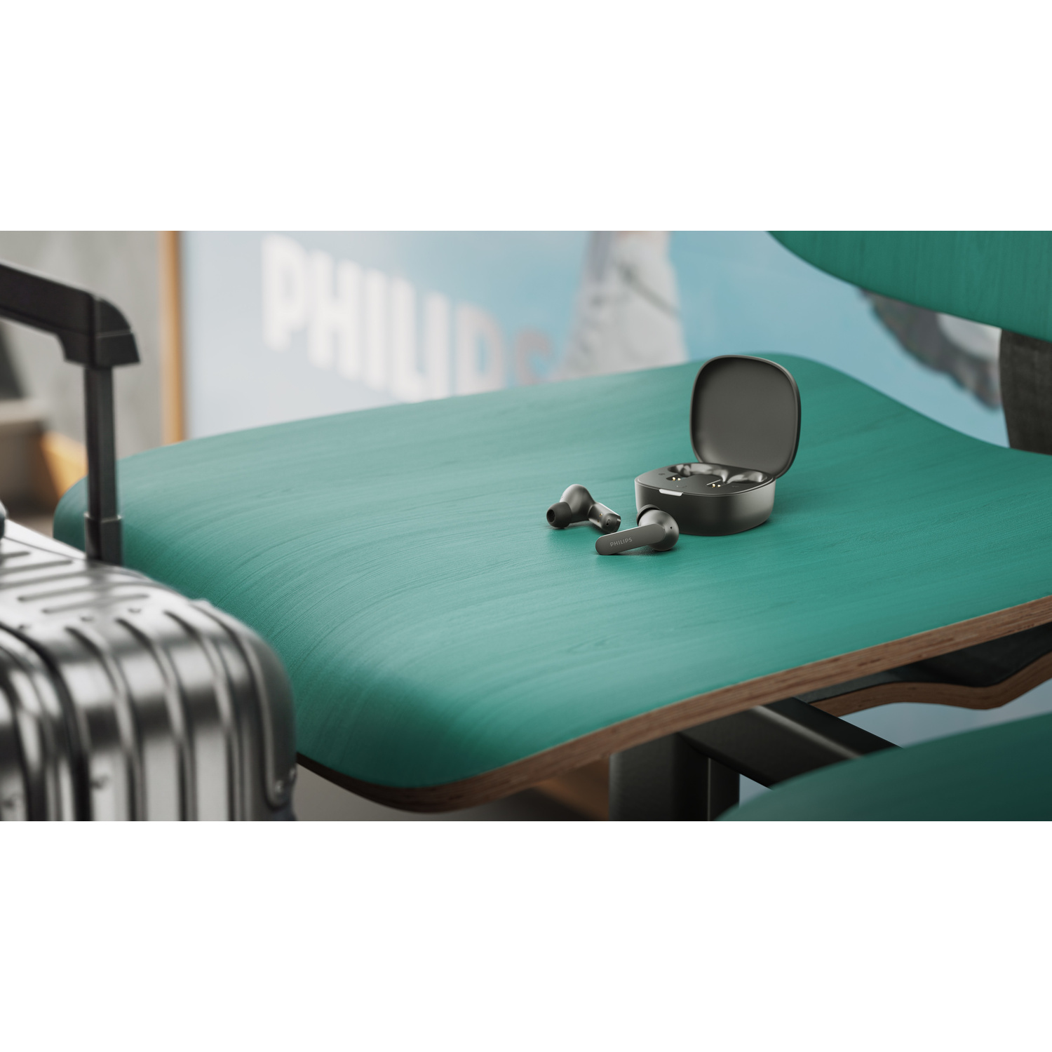 Auricolari wireless neri con custodia di ricarica su una sedia verde vicino a una valigia.