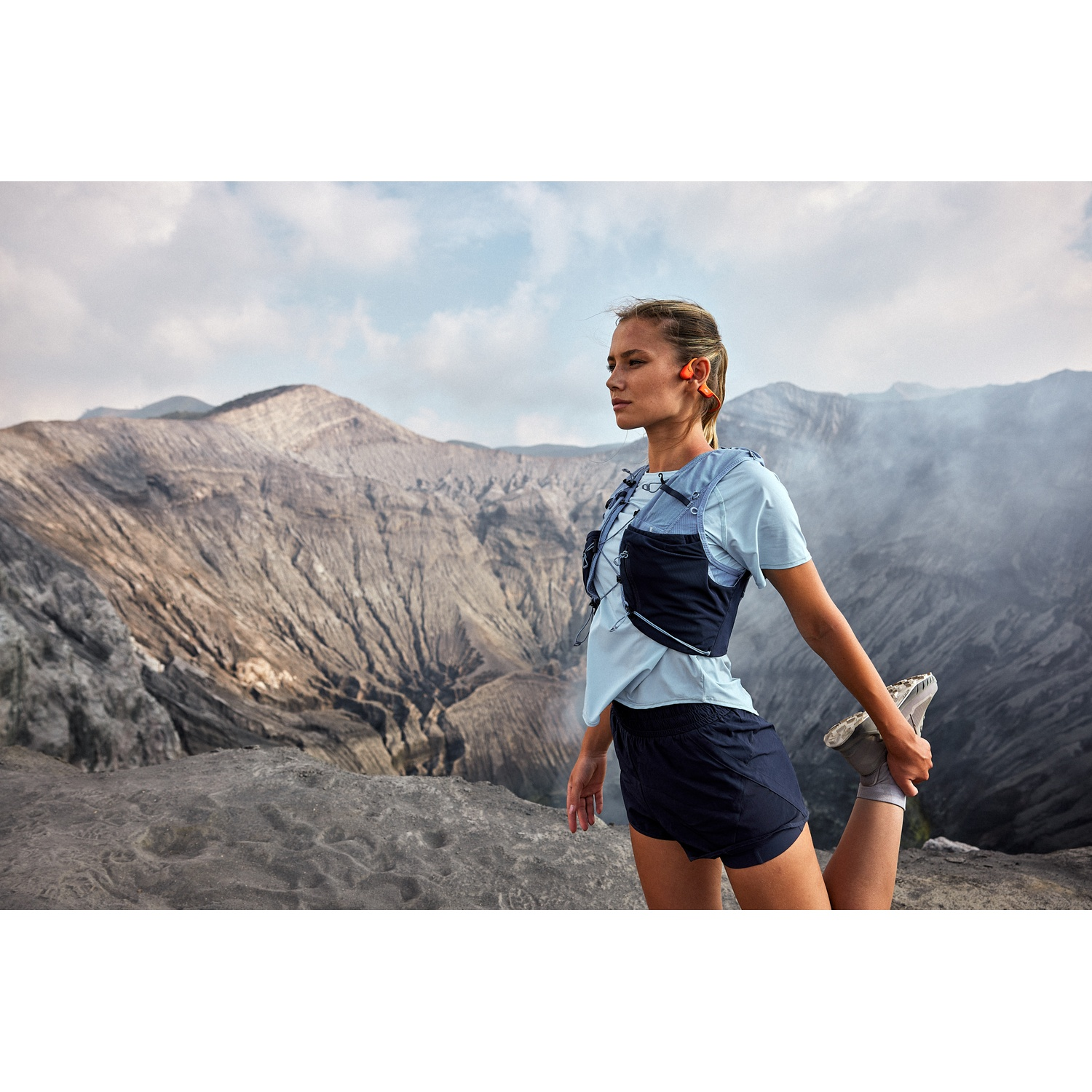 Une femme en tenue de sport s'étire devant un paysage montagneux.