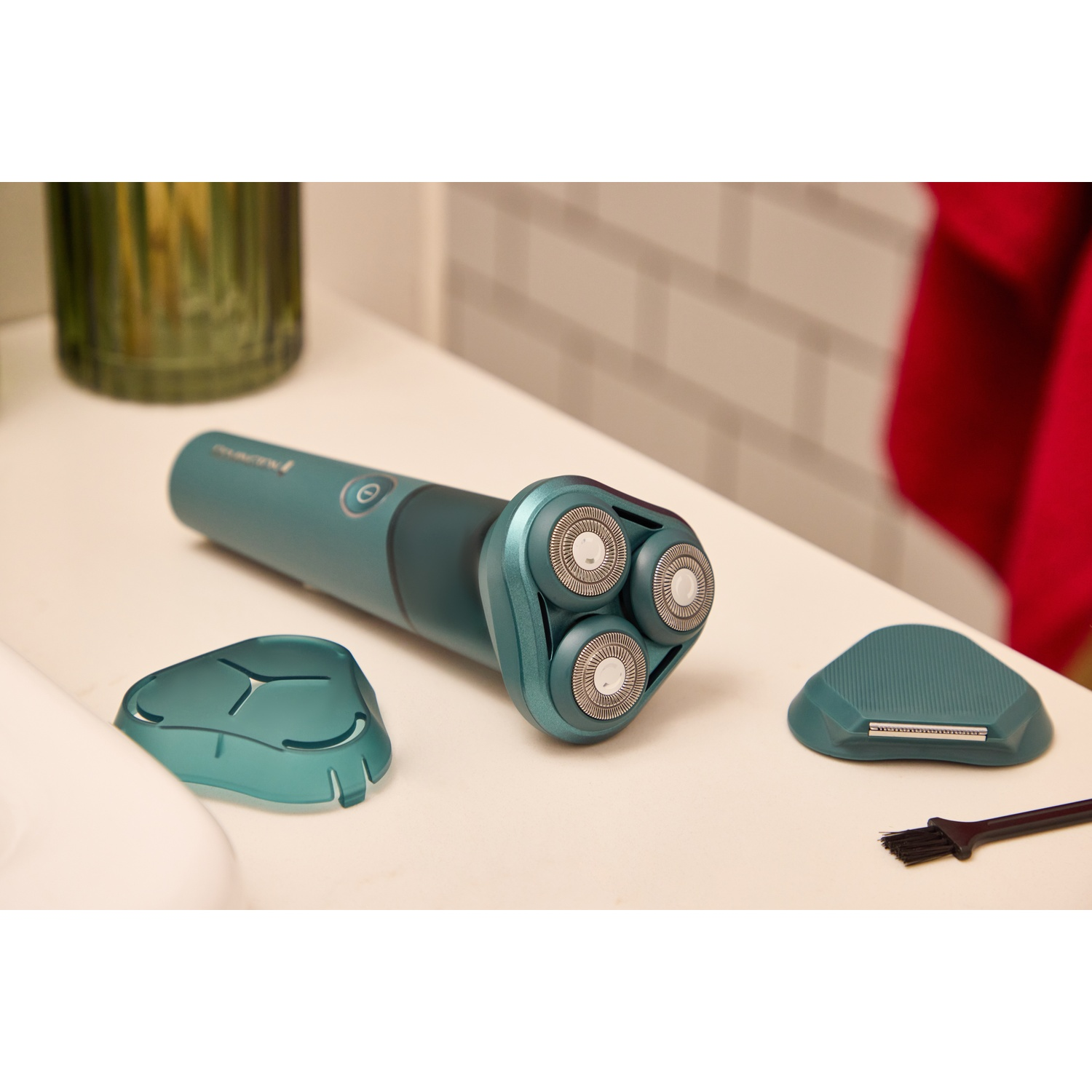 Een turquoise elektrisch scheerapparaat met drie koppen en accessoires.