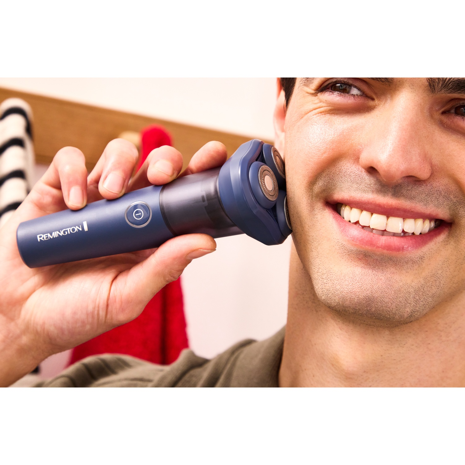 Een man die zijn gezicht scheert met een blauw Remington scheerapparaat.