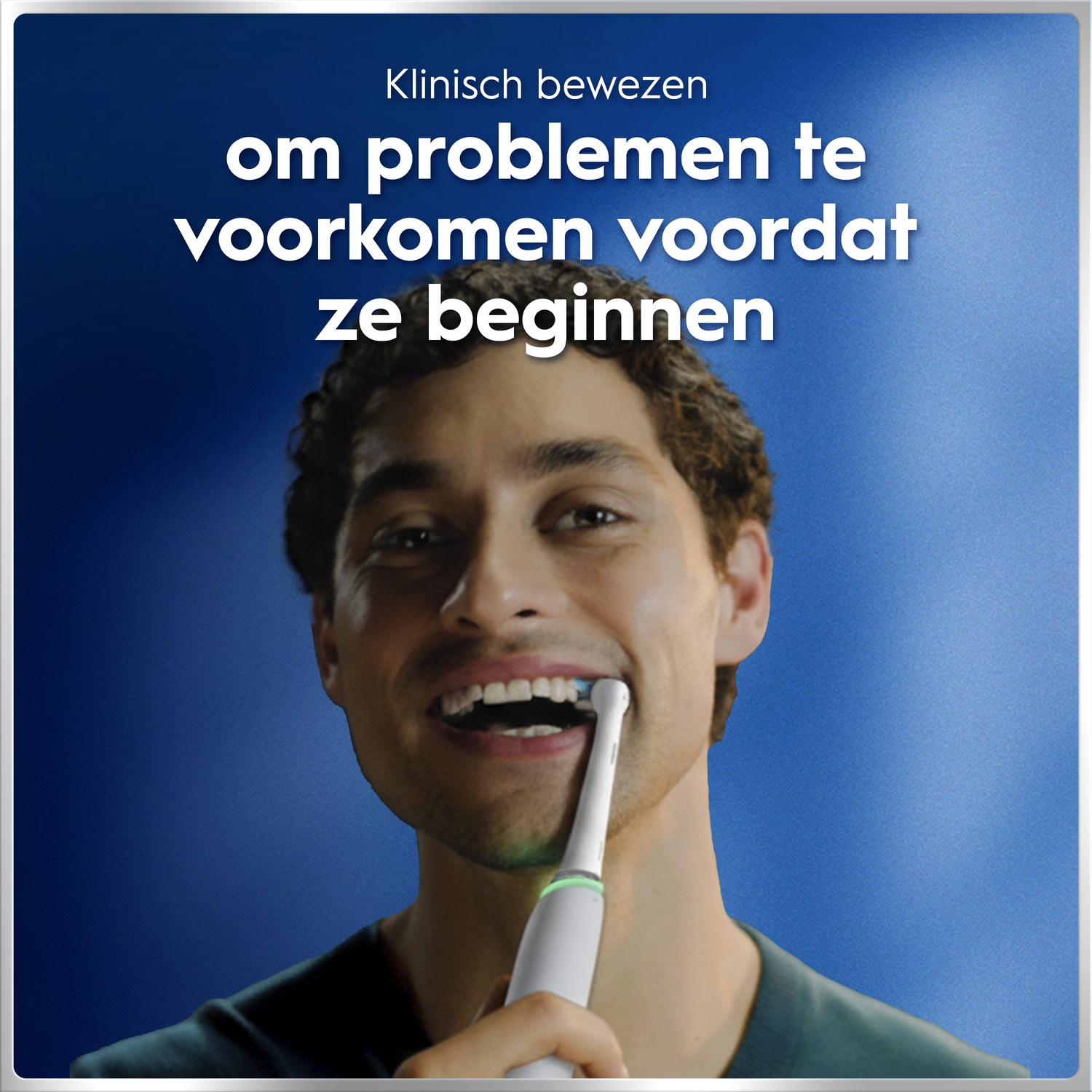 Un homme sourit en se brossant les dents avec une brosse à dents électrique sur fond bleu.