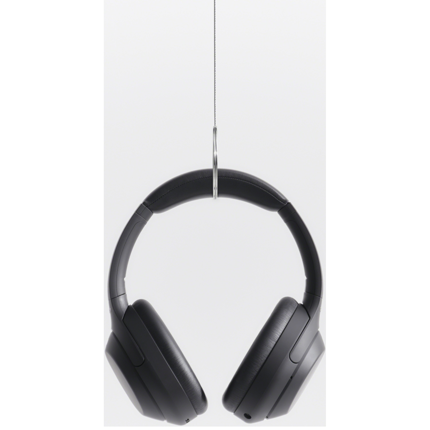 Black over-ear headphones hang from a metal ring against a white background.