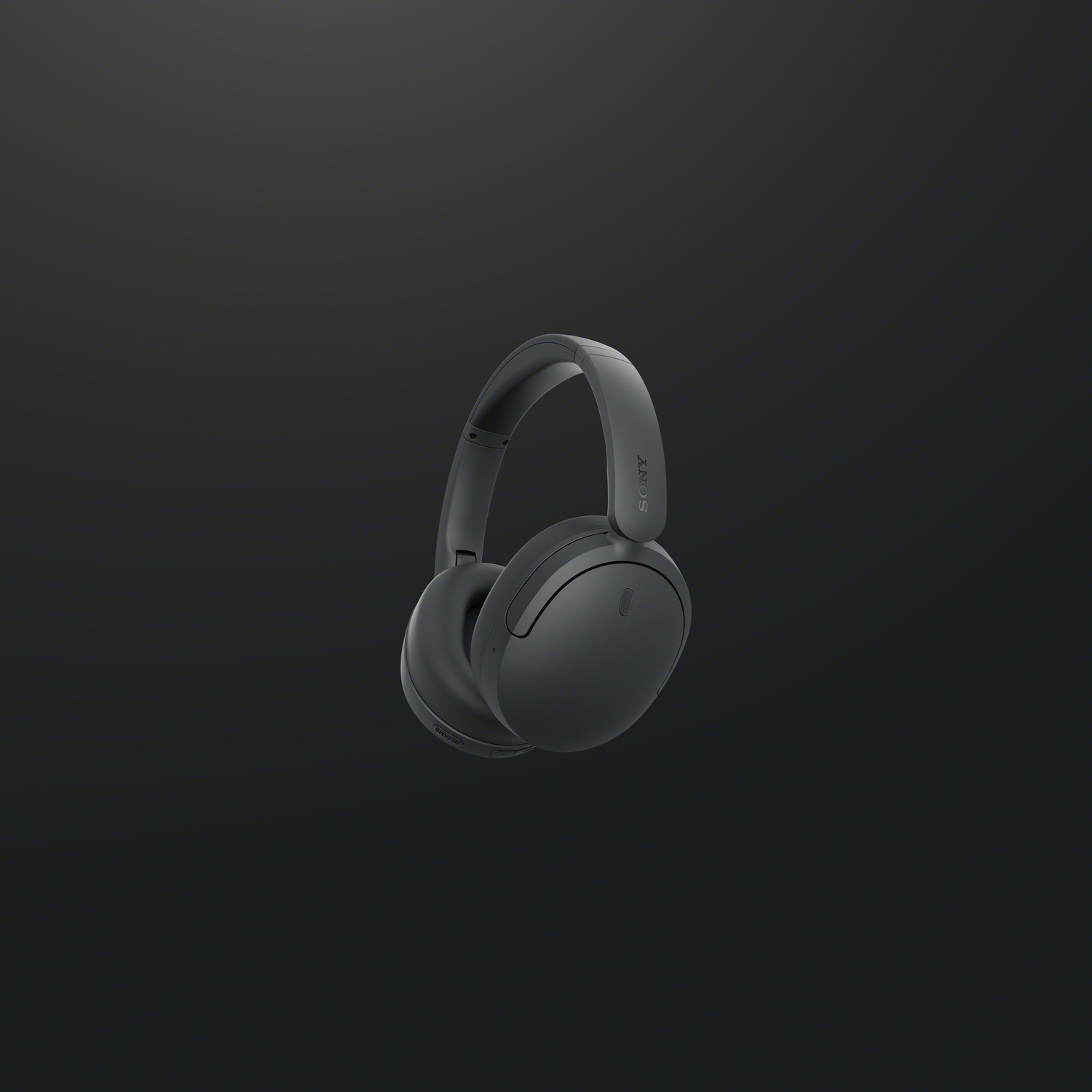Black Sony over-ear headphones on a dark background.