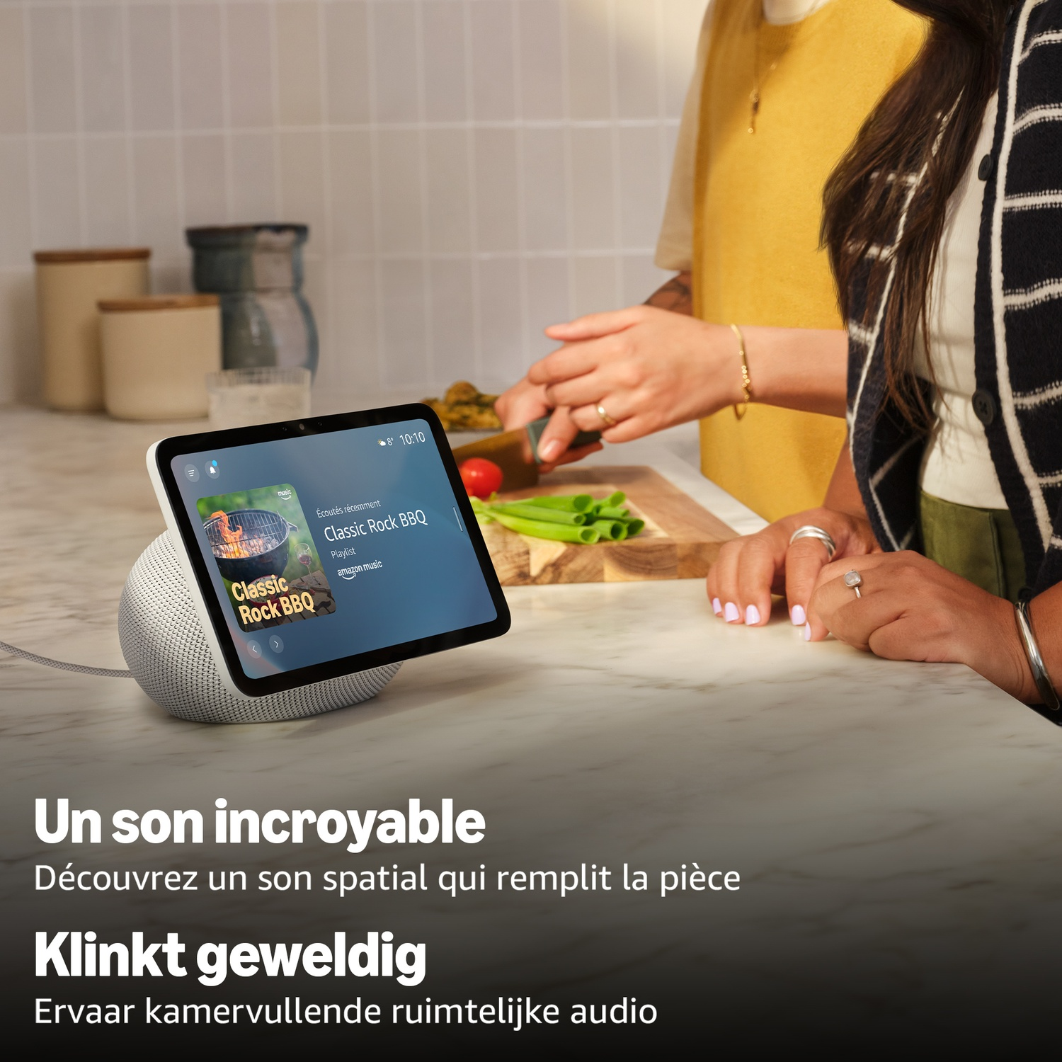 Une enceinte connectée avec écran est posée sur un plan de travail pendant qu'on cuisine.