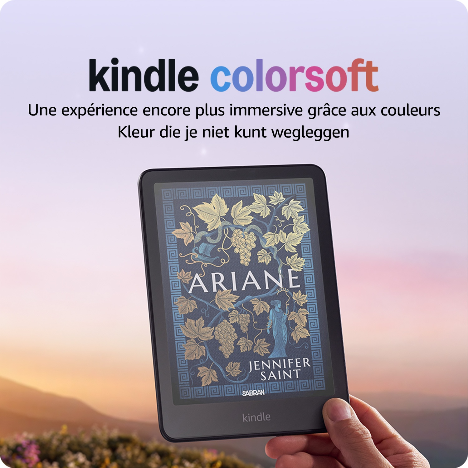 Une main tient une liseuse Kindle Colorsoft affichant la couverture du livre Ariane sur fond de montagnes floues.