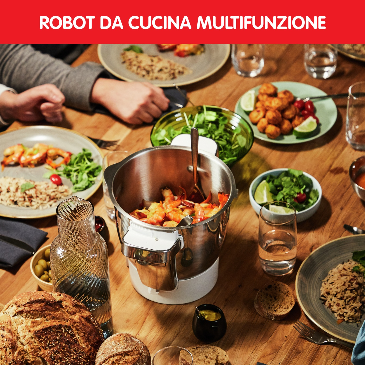 Un tavolo in legno con piatti, insalata, pane e un robot da cucina multifunzione con gamberi.