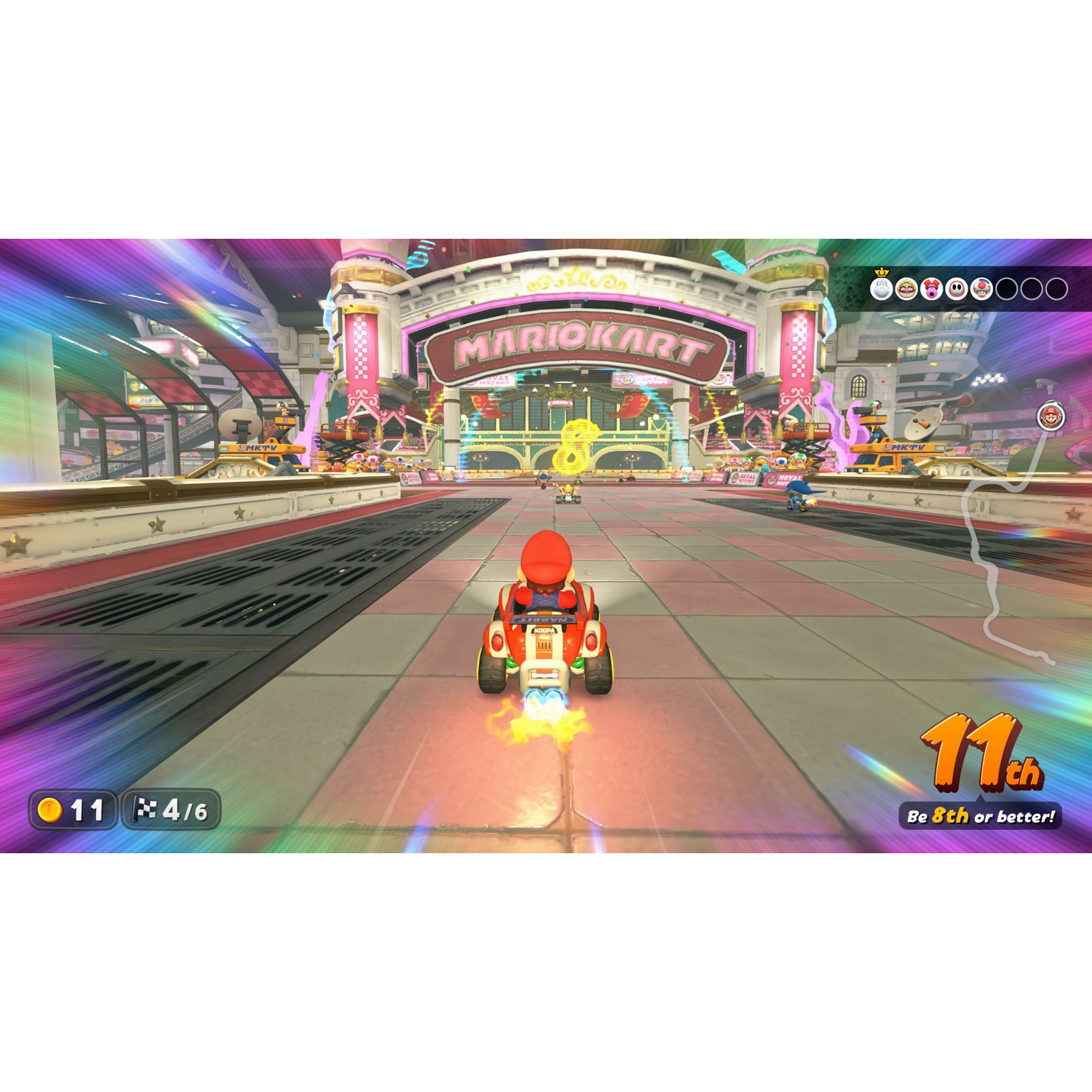 Mario rijdt in een rode kart op een Mario Kart-baan, omringd door kleurrijke lichten.