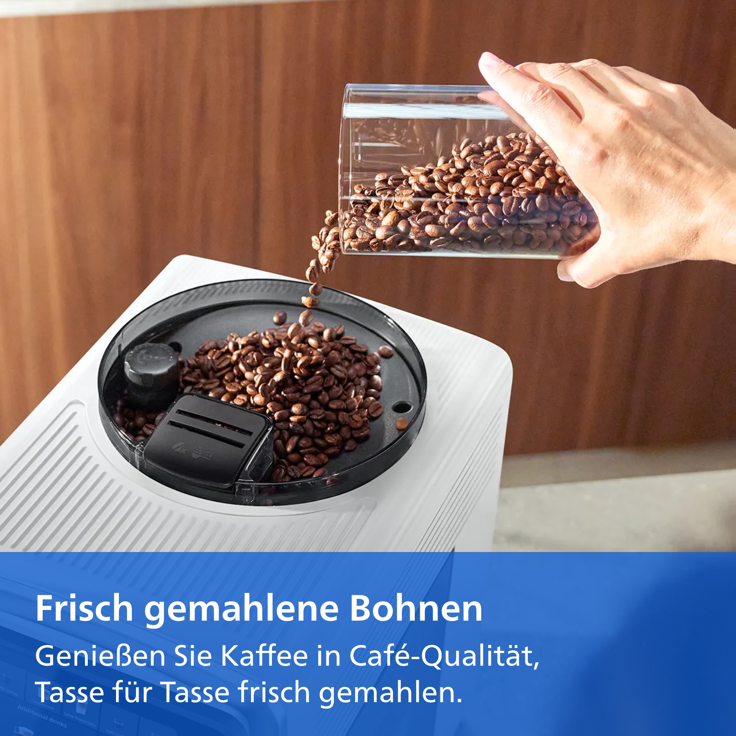 Hand gießt Kaffeebohnen aus einem Behälter in eine weiße Kaffeemaschine.