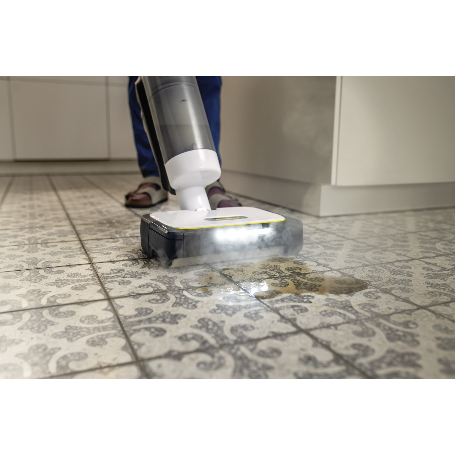 Un nettoyeur de sol désinfecte des carreaux à motifs, éliminant une tache.