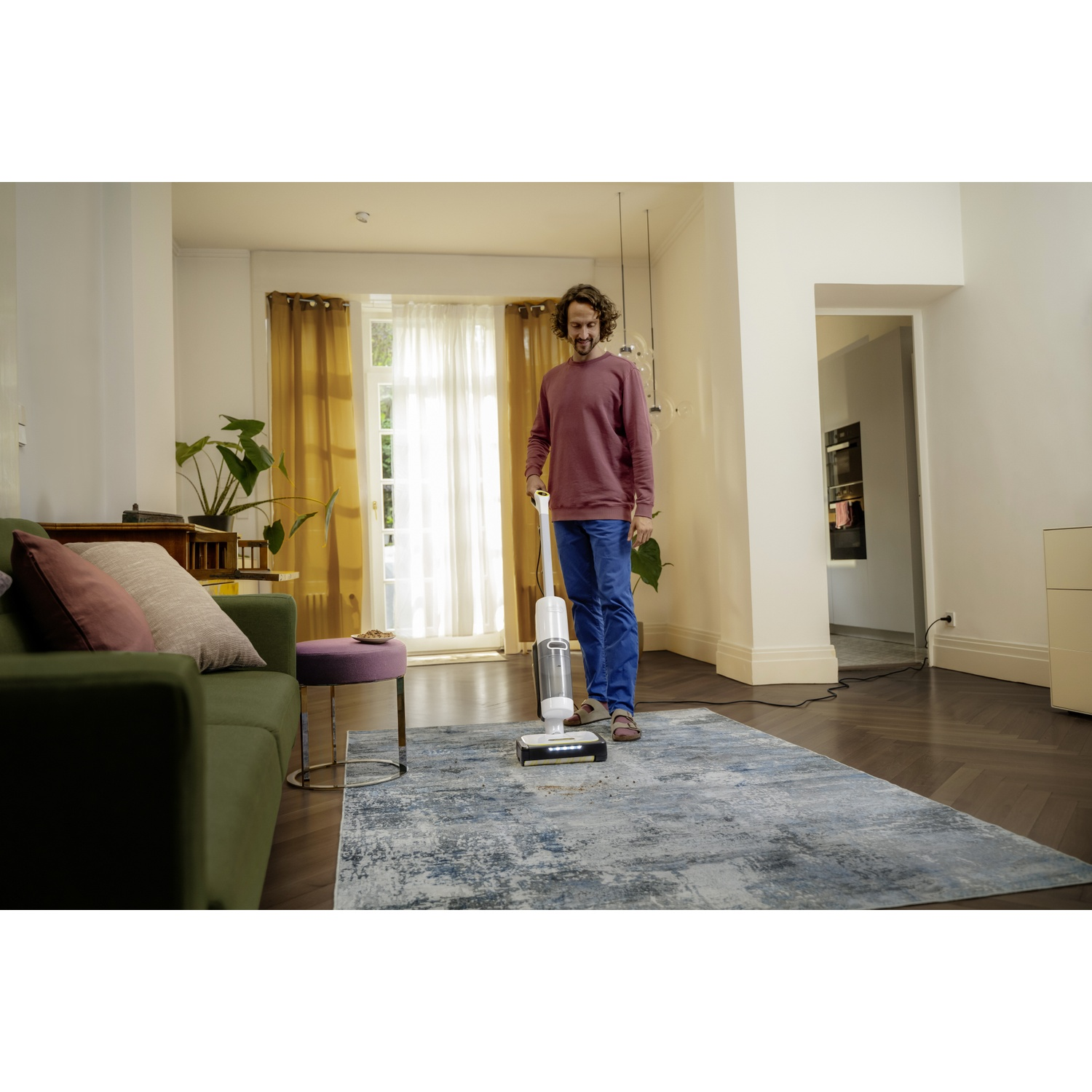 Un homme utilise un aspirateur eau et poussière sur un tapis dans un salon moderne.