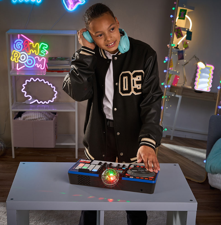 Ein Junge in einer Jacke legt an einem DJ-Pult mit bunten Lichtern in einem bunten Zimmer auf.
