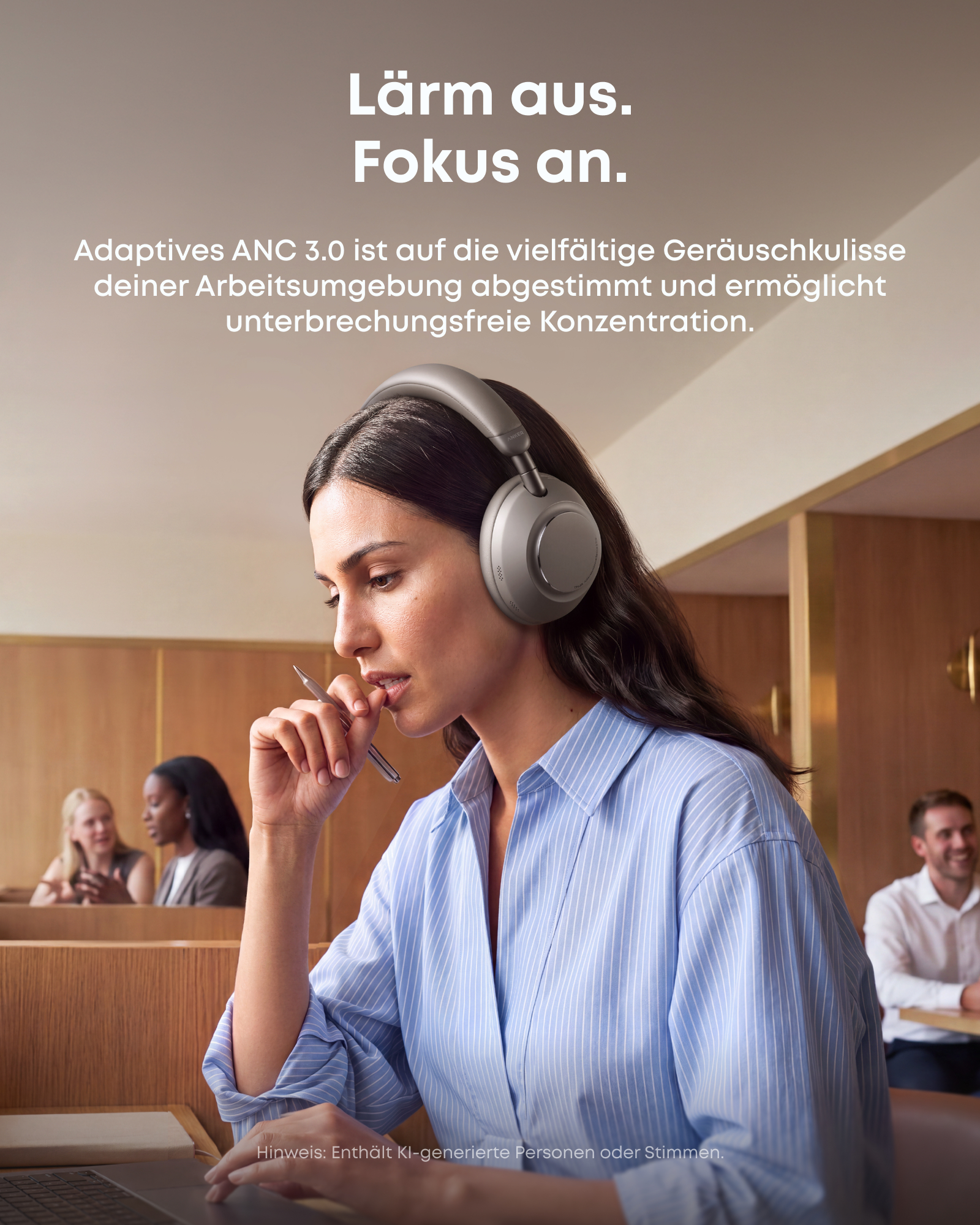 Eine Frau mit grauen Kopfhörern arbeitet in einem Café mit anderen Menschen im Hintergrund an einem Laptop.