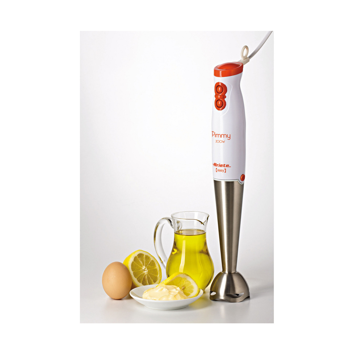 Un frullatore a immersione bianco con dettagli arancioni accanto a un uovo, una fetta di limone, olio e maionese.