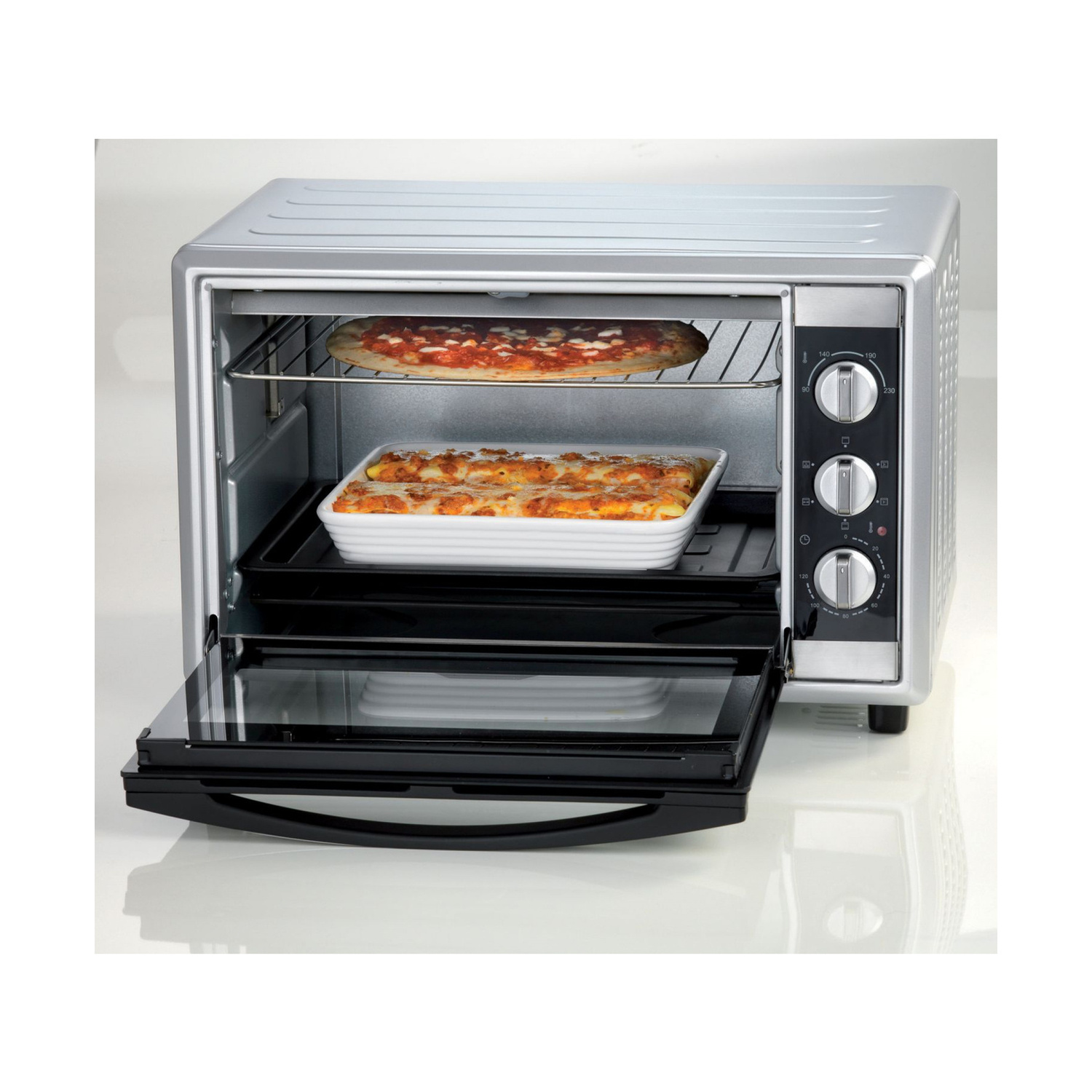 Un mini forno argentato con la porta aperta, cuoce una pizza sopra e una casseruola sotto.