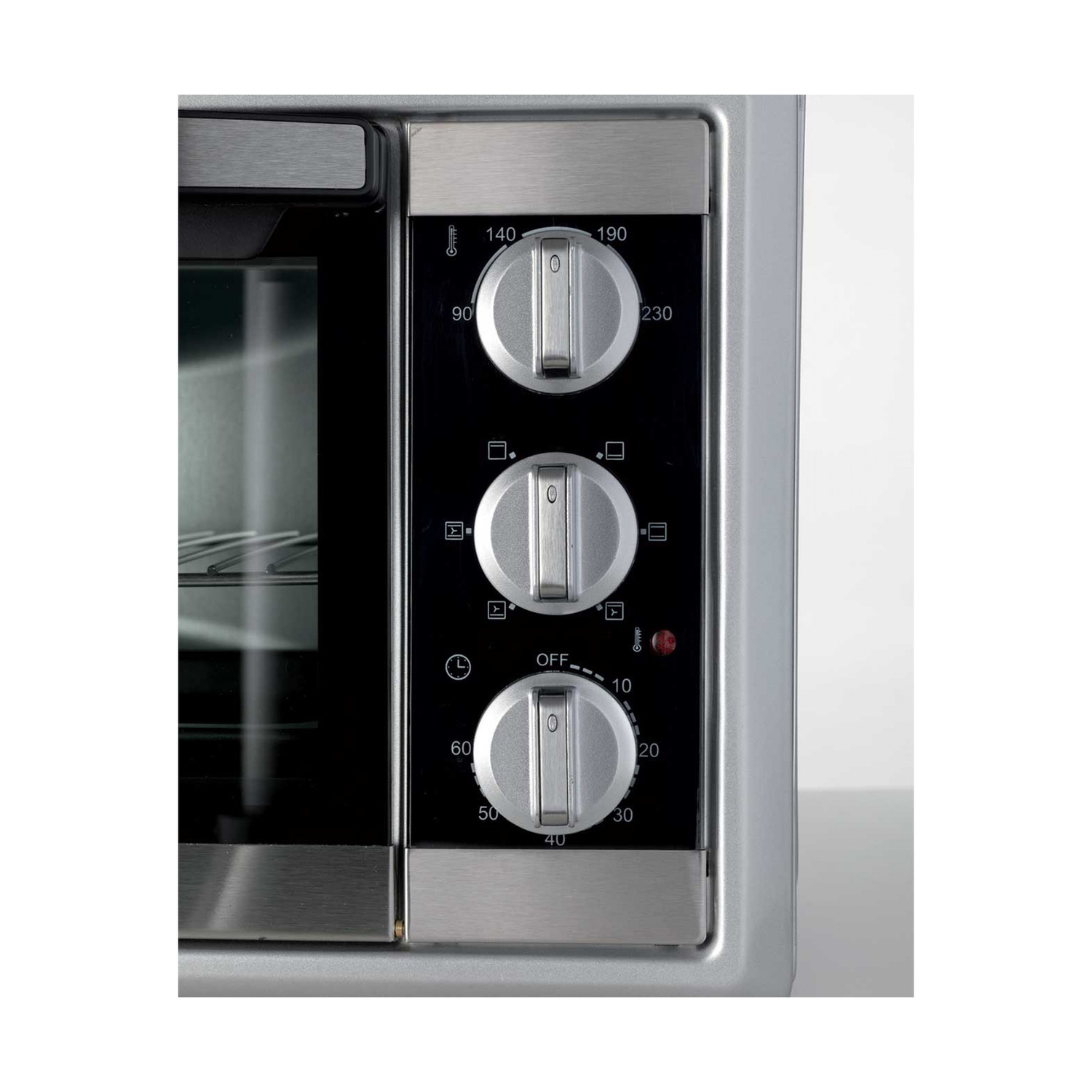Pannello di controllo di un mini forno argentato con tre manopole rotonde e una spia rossa.