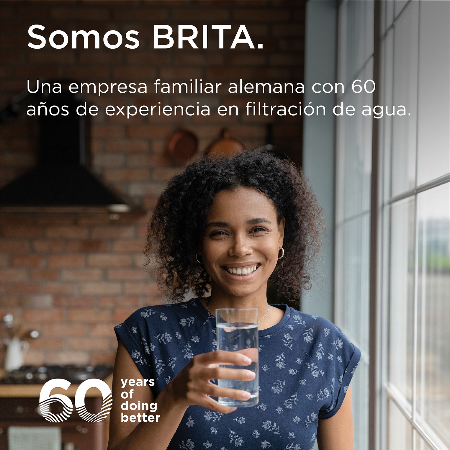 Mujer sonriente sostiene un vaso de agua en la cocina, texto sobre BRITA.