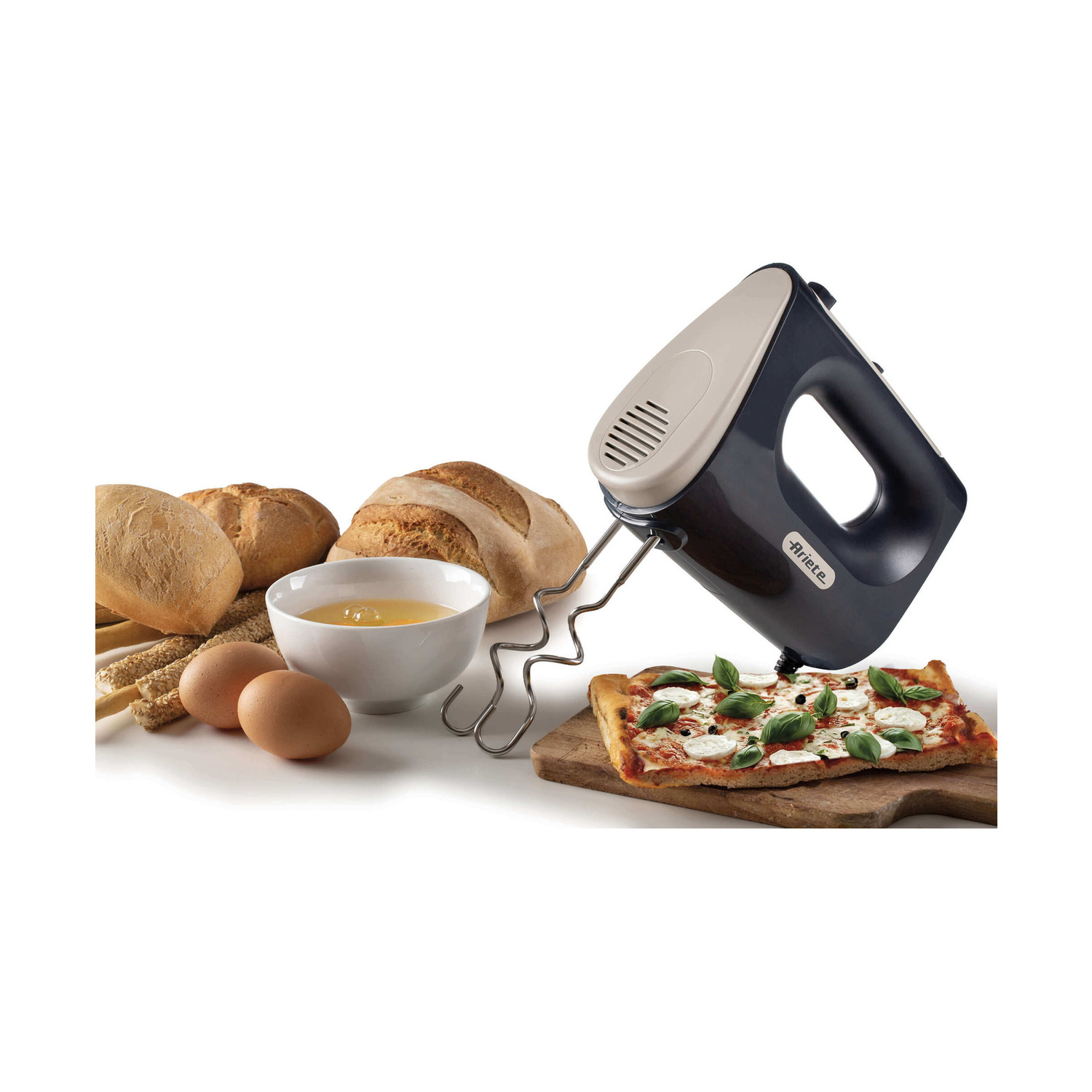 Un mixer a mano accanto a pane, uova in una ciotola e pizza su un tagliere.