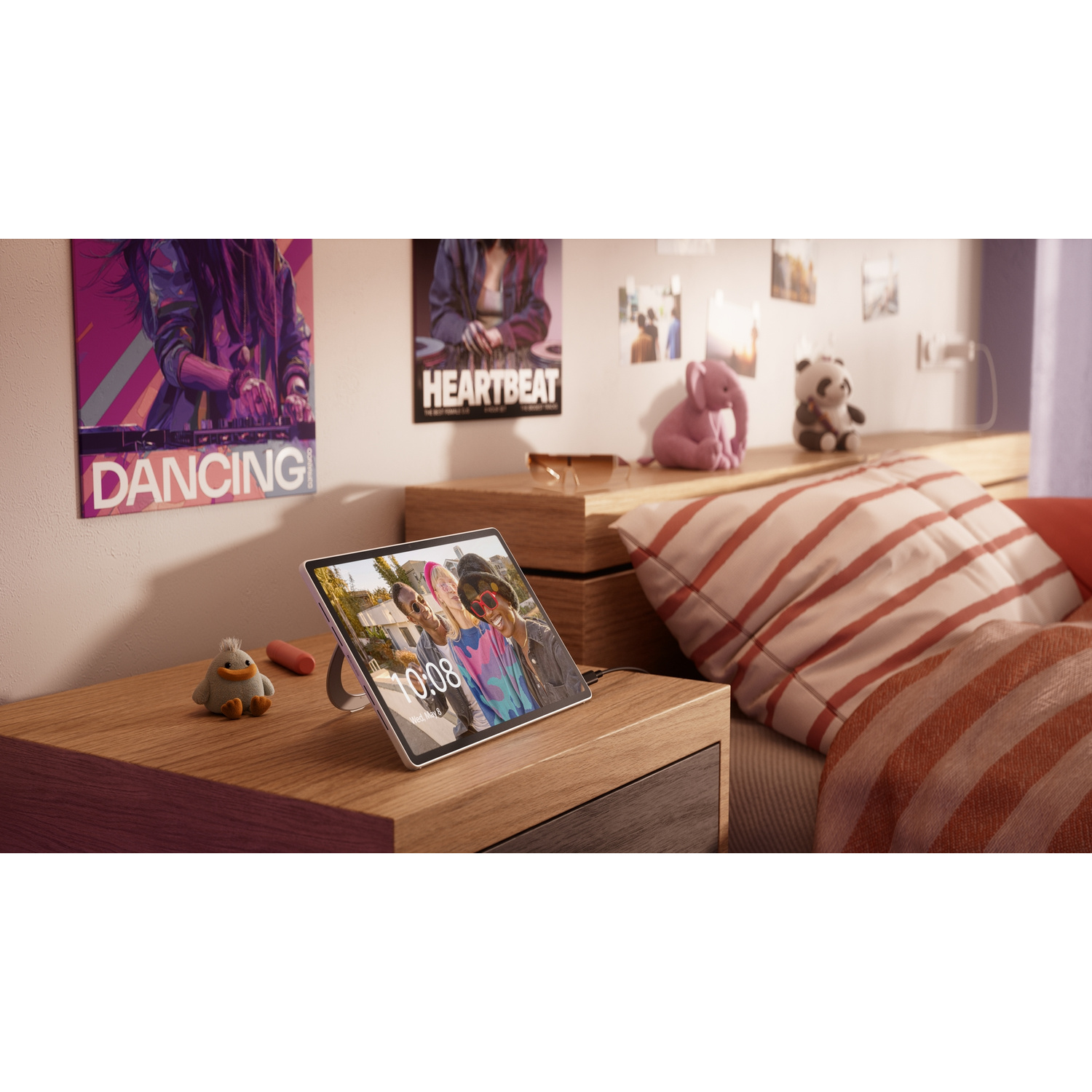 Un tablet su un comodino di legno in una camera da letto, che mostra la foto di amici. Poster e peluche decorano la stanza.