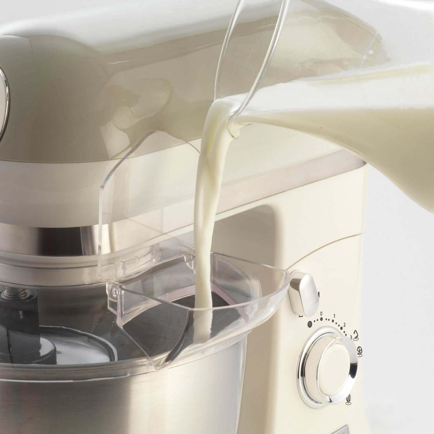 Il latte viene versato da una brocca nell'imbuto di una planetaria color crema.