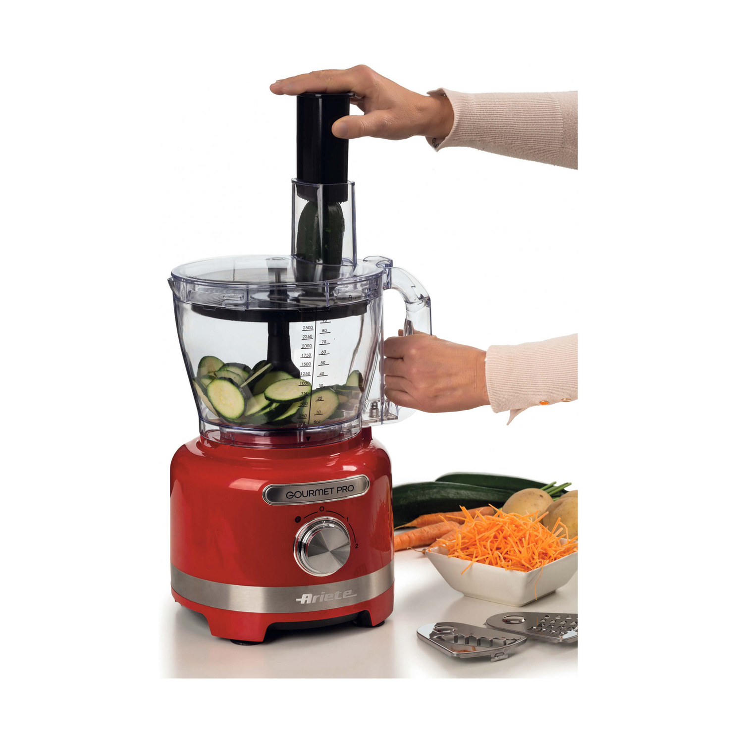 Persona che aziona un robot da cucina rosso Ariete Gourmet Pro con zucchine affettate.