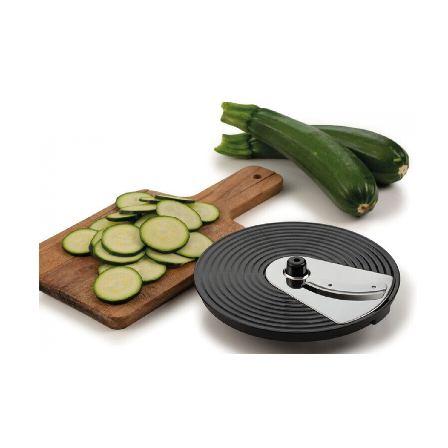 Due zucchine, fette su un tagliere di legno e un affettaverdure rotondo su sfondo bianco.