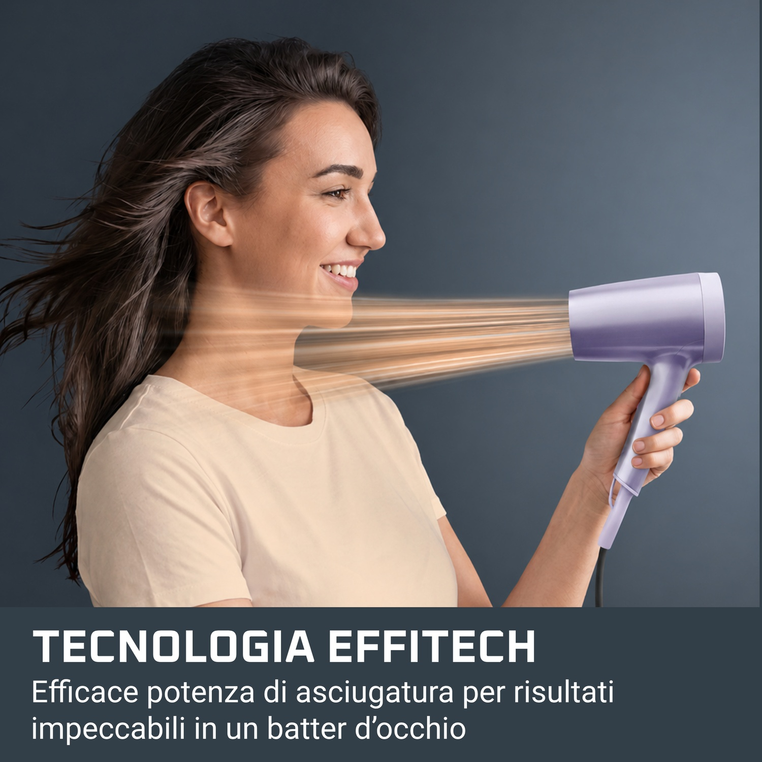 Una donna sorride asciugandosi i capelli con un phon viola su sfondo grigio.
