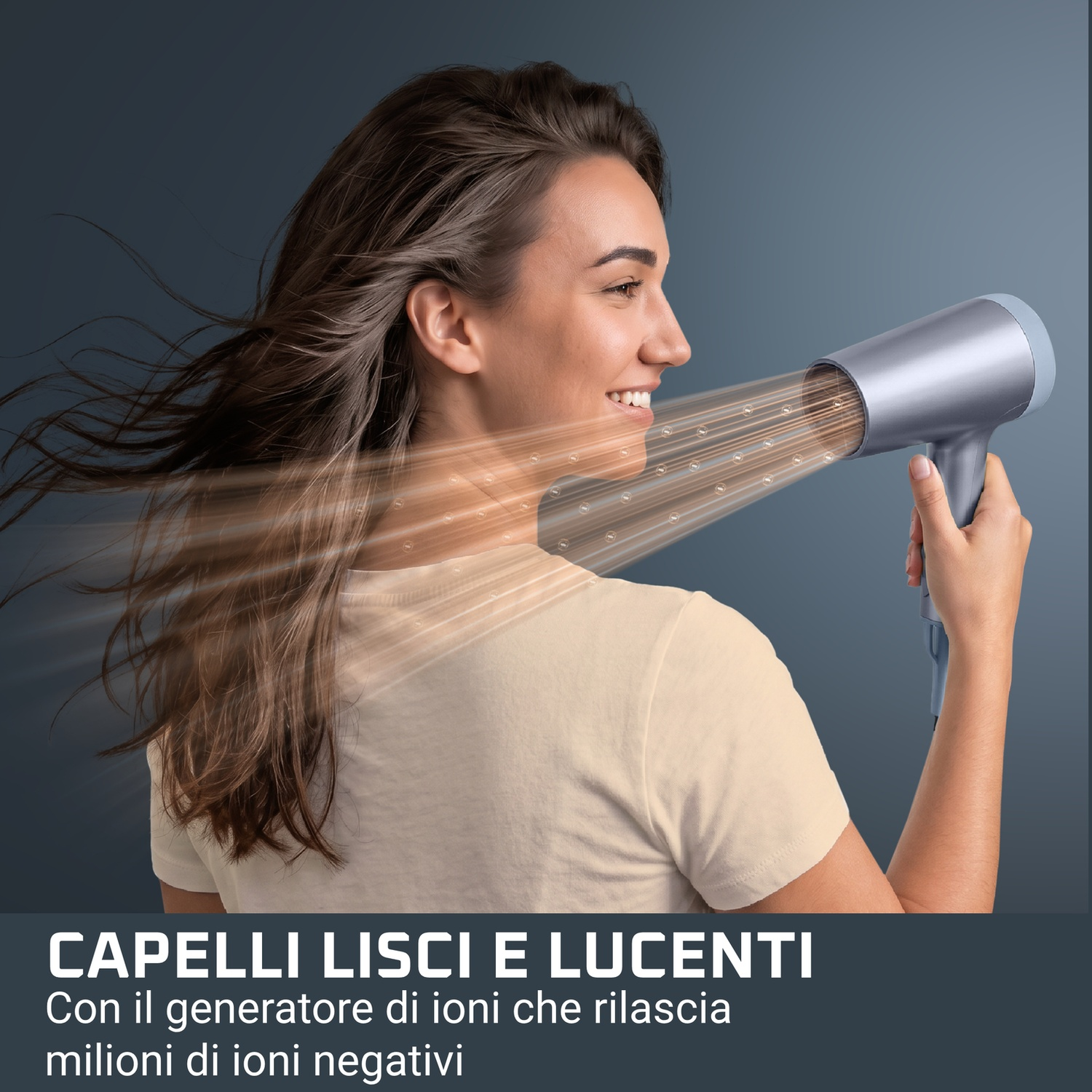 Una donna sorridente si asciuga i capelli con un phon argentato, con i capelli al vento.