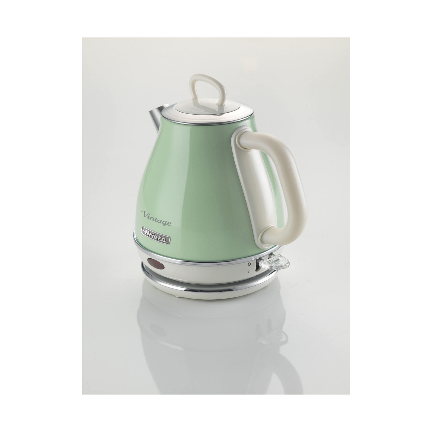 Un bollitore elettrico vintage verde menta con manico bianco su una base lucida su sfondo bianco.