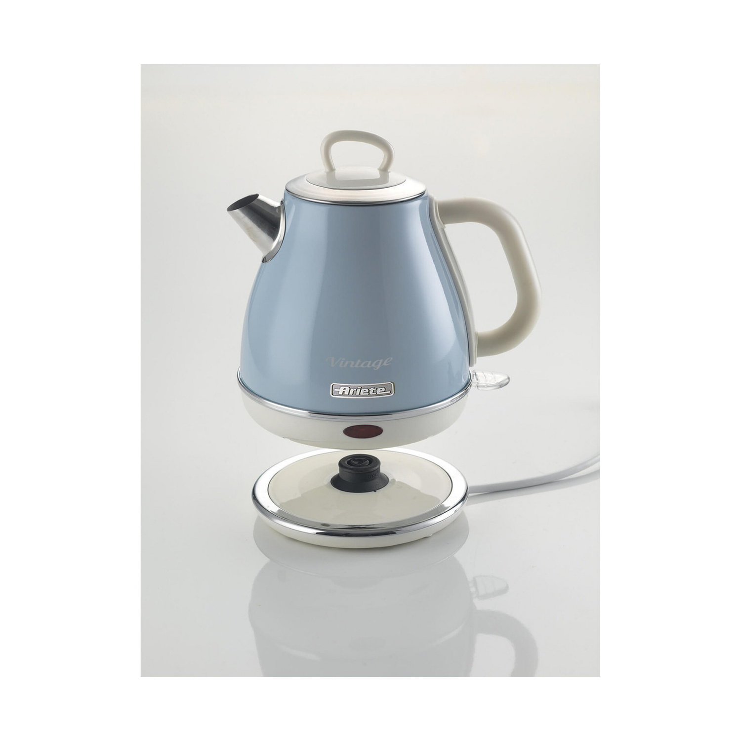 Un bollitore elettrico vintage Ariete blu fluttua sopra la sua base bianca su sfondo chiaro.