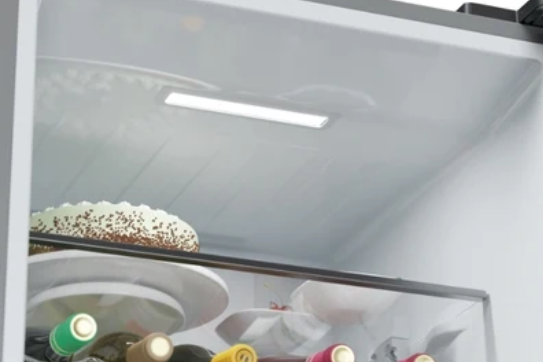 Una luz LED brillante ilumina el interior superior de un refrigerador moderno con alimentos.