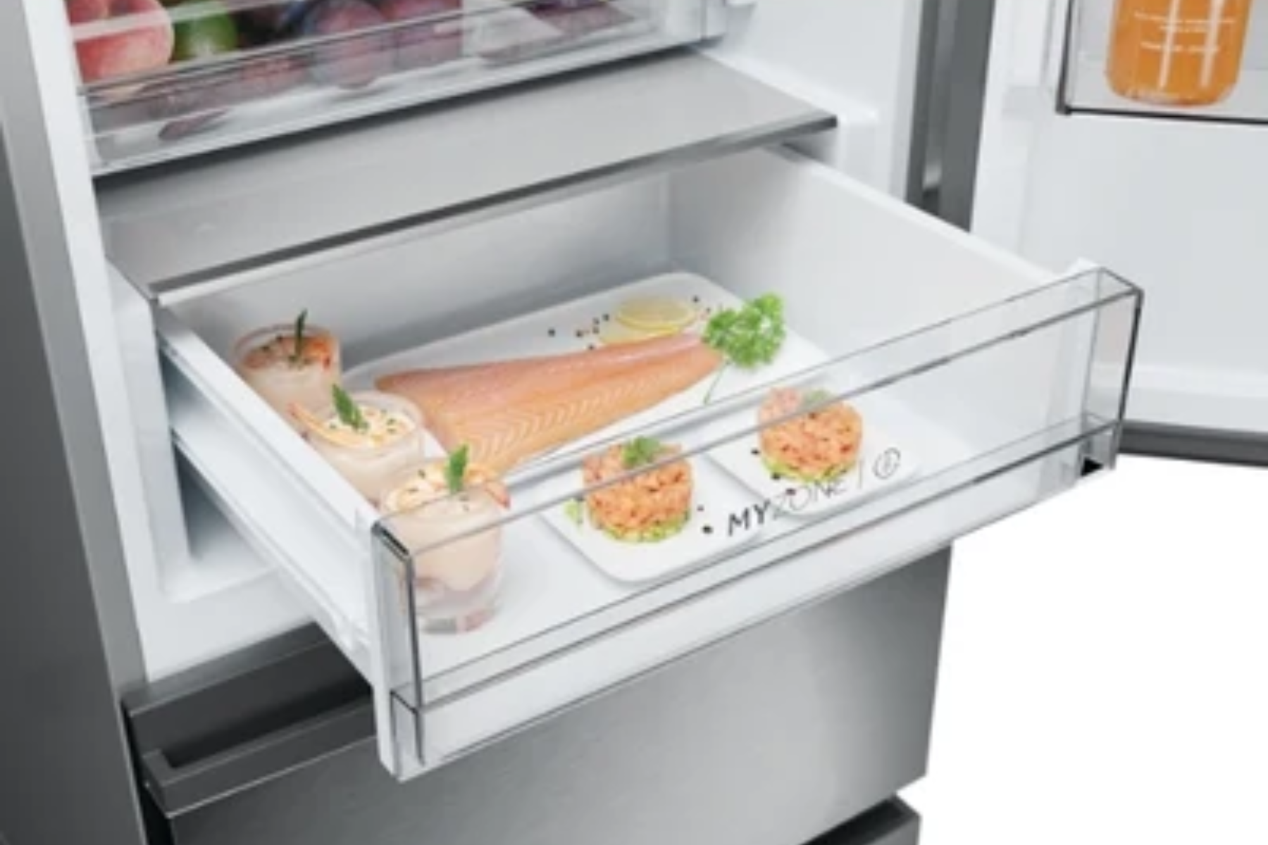 Cajón de refrigerador abierto con pescado crudo, camarones y platos preparados.
