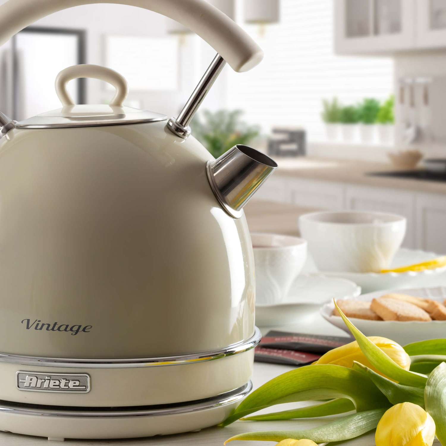 Bollitore vintage beige Ariete su un tavolo con tulipani gialli in cucina.