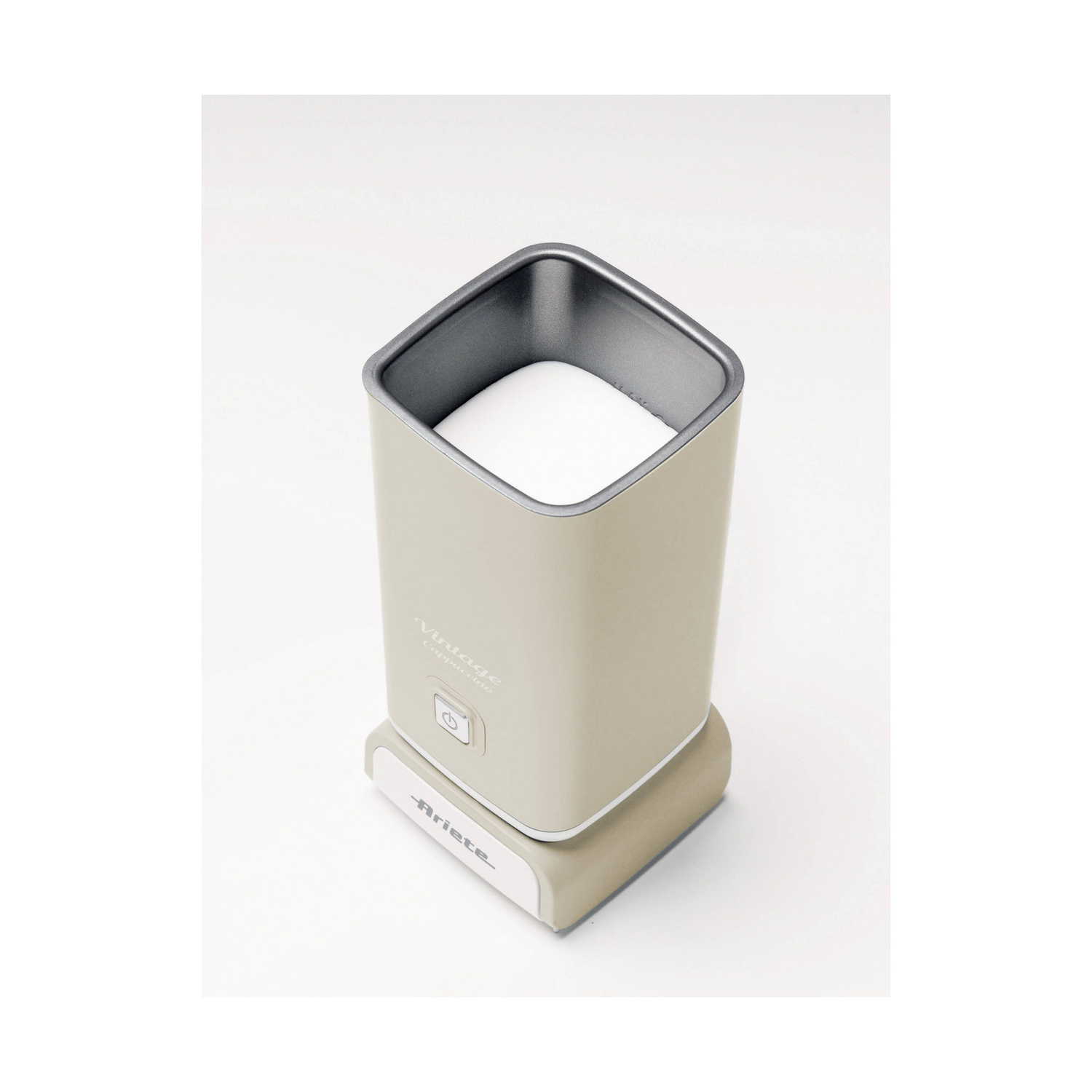 Un montalatte elettrico beige si trova su una superficie bianca, con schiuma bianca visibile all'interno.