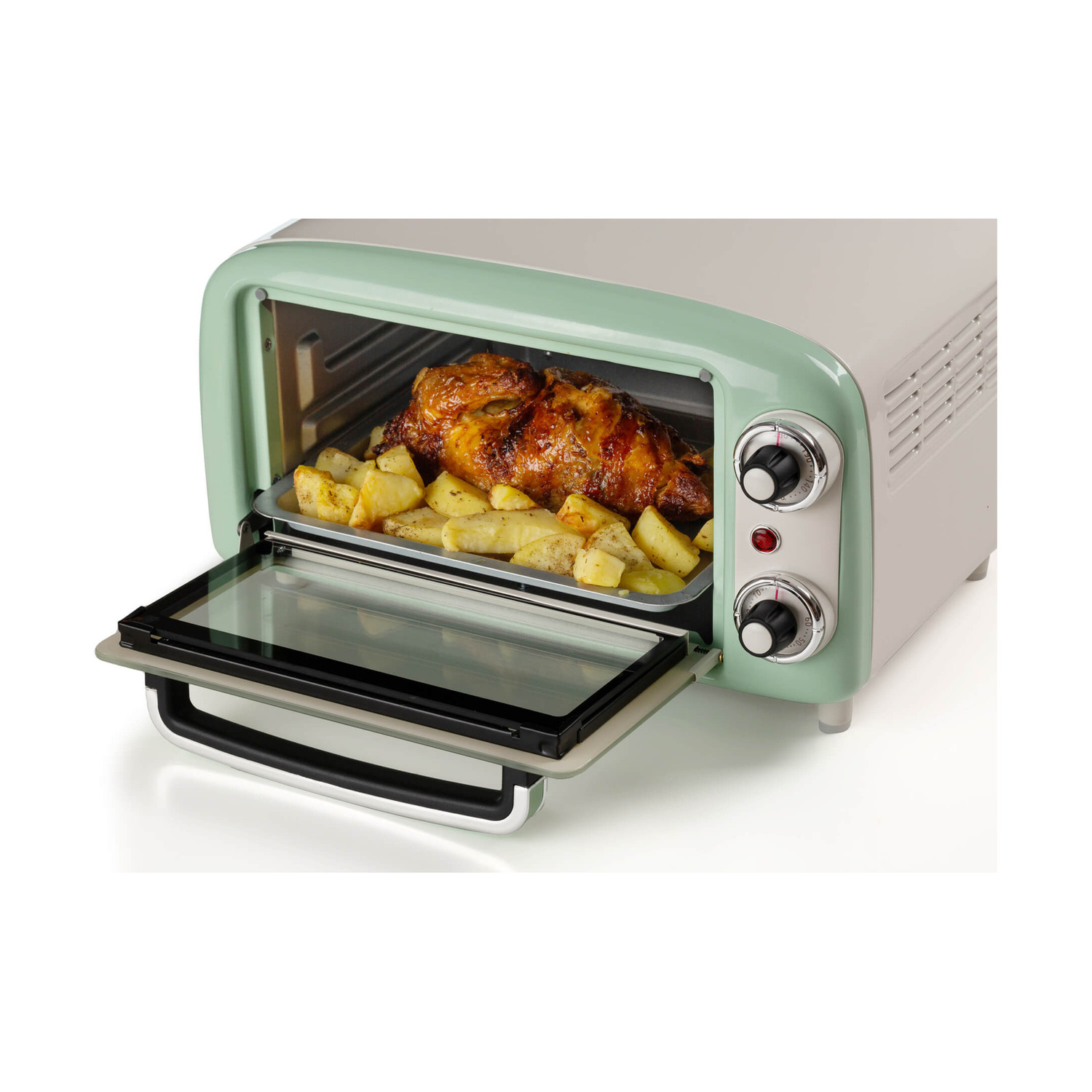 Un mini forno verde menta con un pollo arrosto e patate all'interno su una teglia.