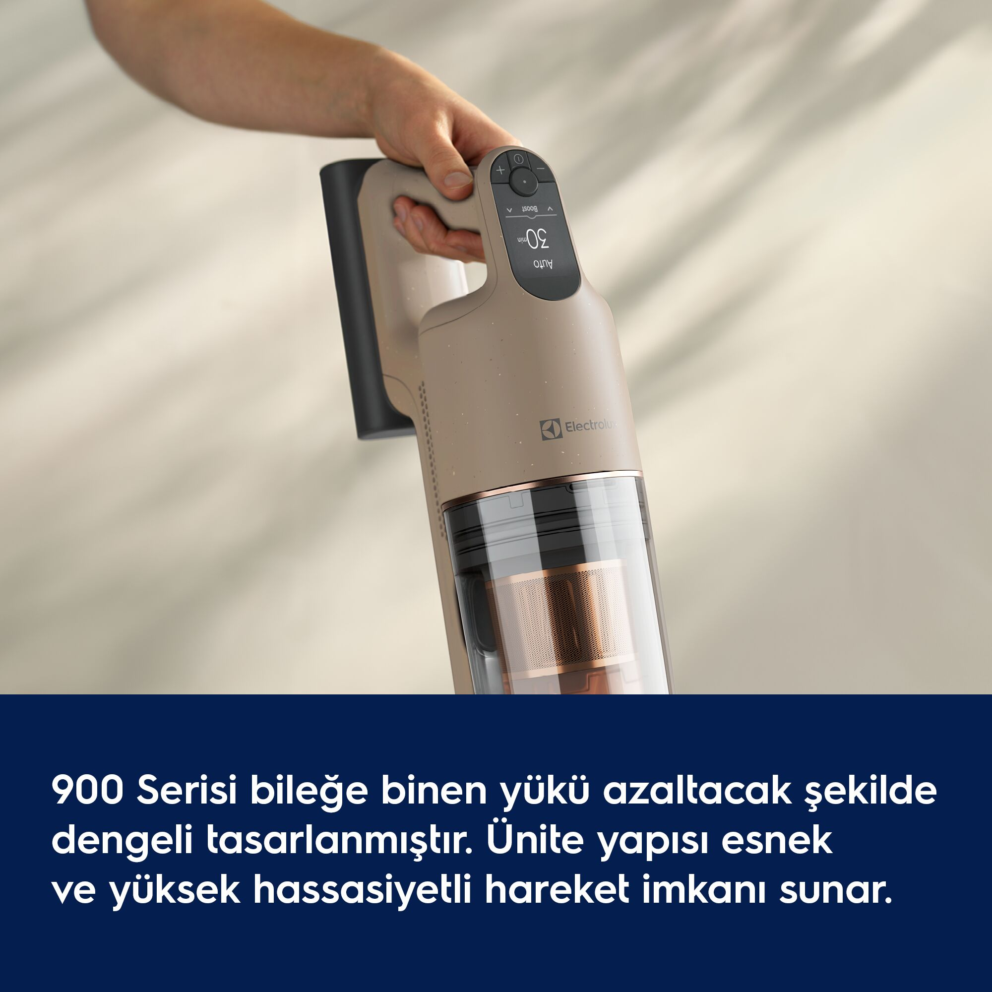 Bir el, açık renkli fon önünde bej renkli dikey bir elektrikli süpürge tutuyor.