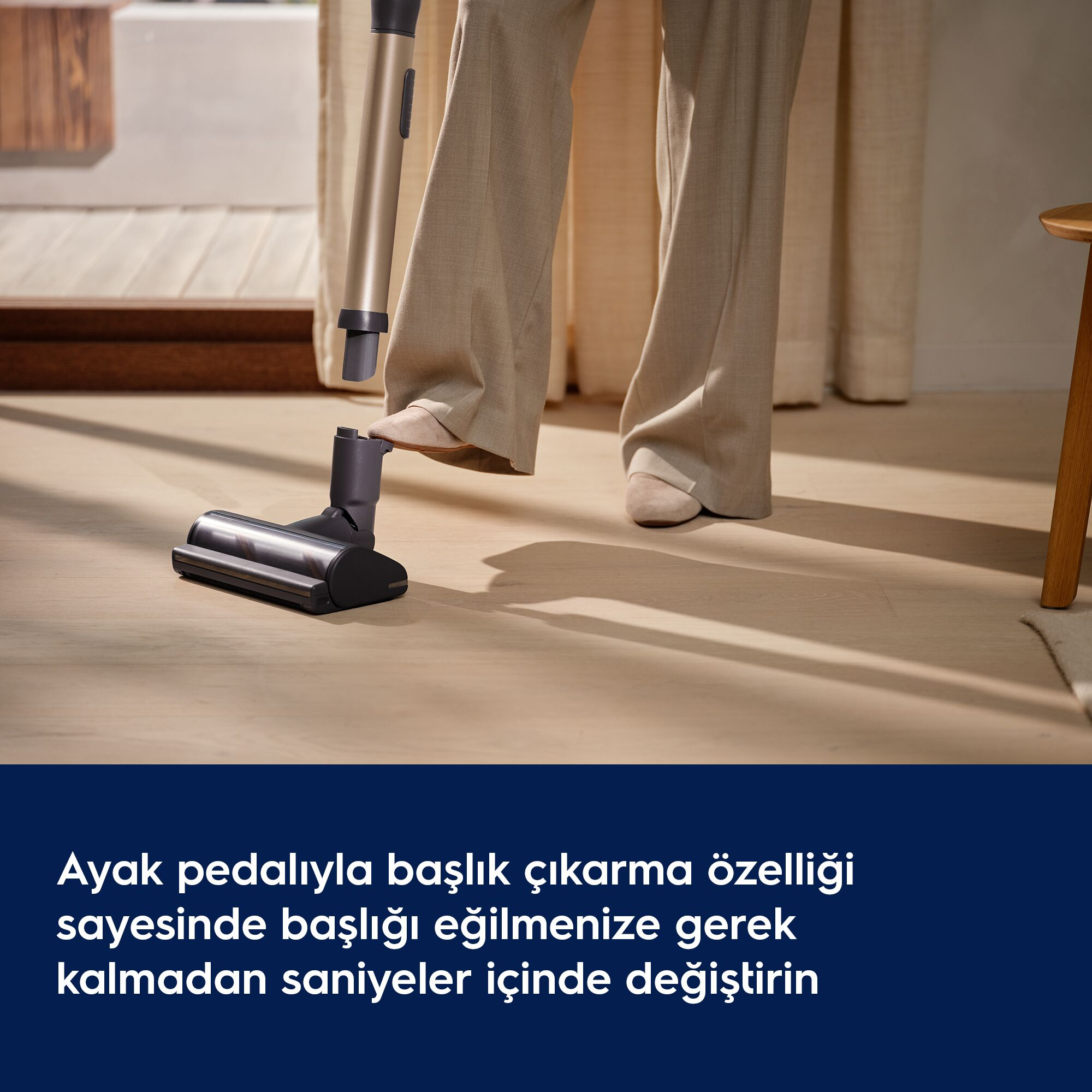 Bir kişi ayağıyla elektrikli süpürgenin başlığını ayırıyor.