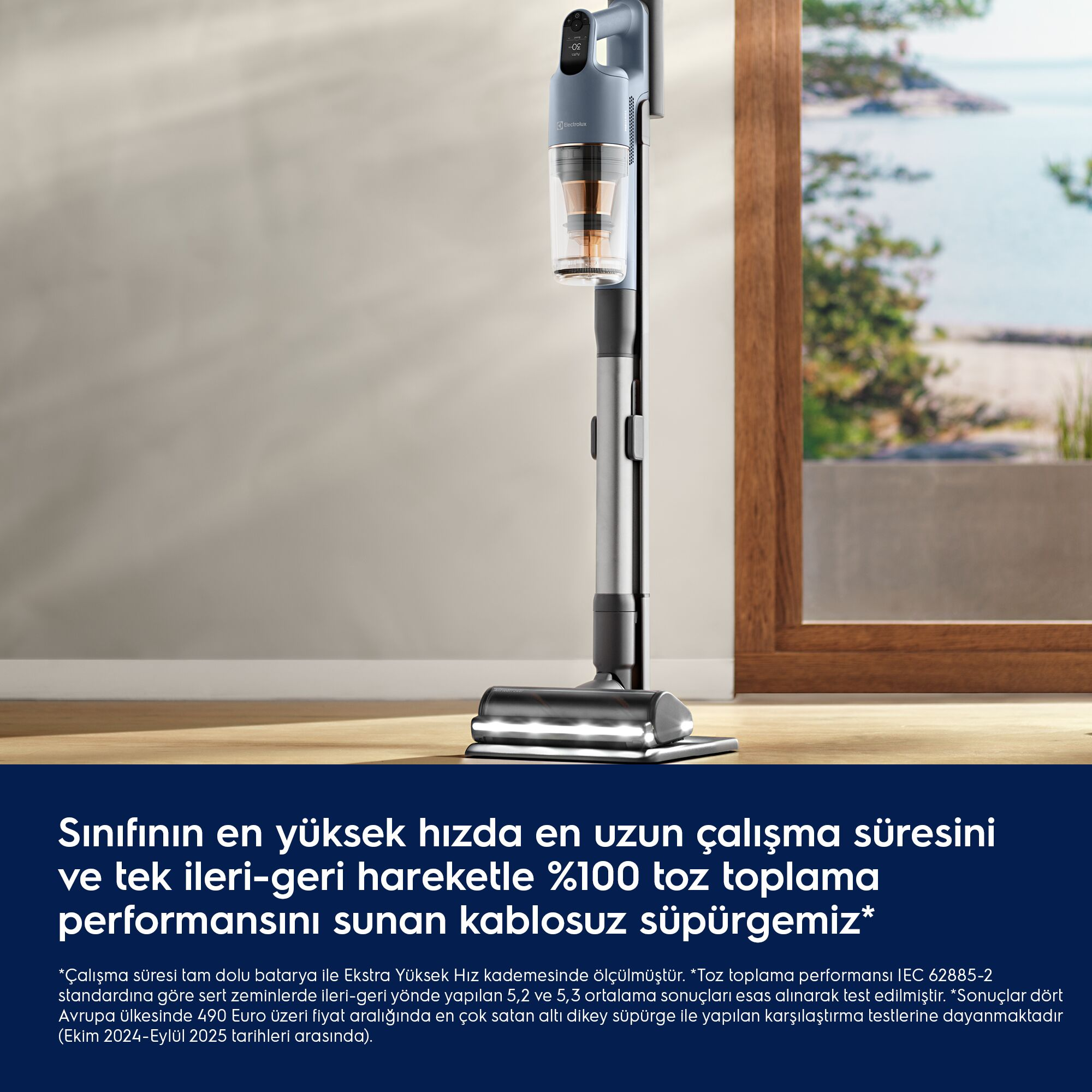 Ahşap zeminde duran modern gri dikey kablosuz süpürge, deniz manzaralı pencerenin önünde.