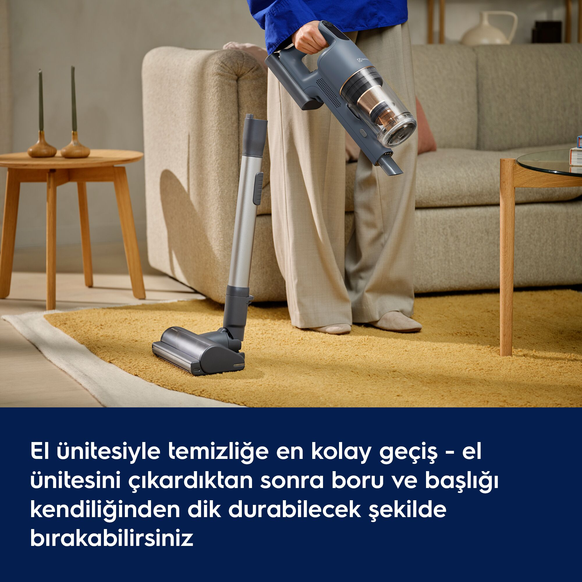 Bir kişi el süpürgesini tutarken boru ve başlık halı üzerinde dik duruyor.