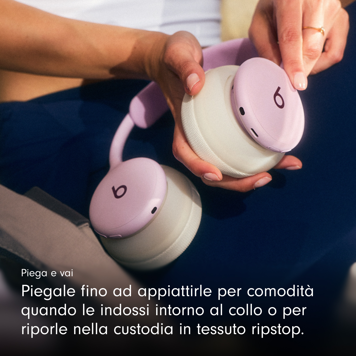 Persona che tiene in mano cuffie pieghevoli rosa e bianche.