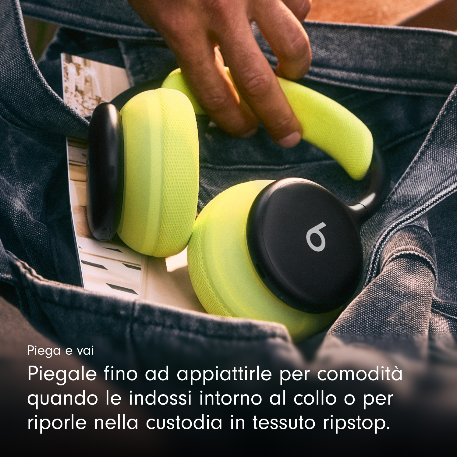 Mano che ripone cuffie gialle e nere in una borsa di jeans.
