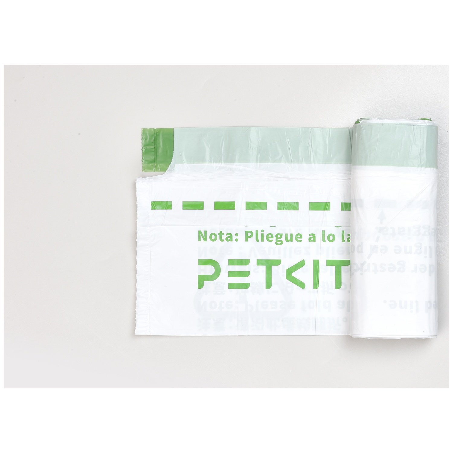 Un rouleau de sacs poubelle Petkit blancs et verts sur fond gris, un sac partiellement déroulé.