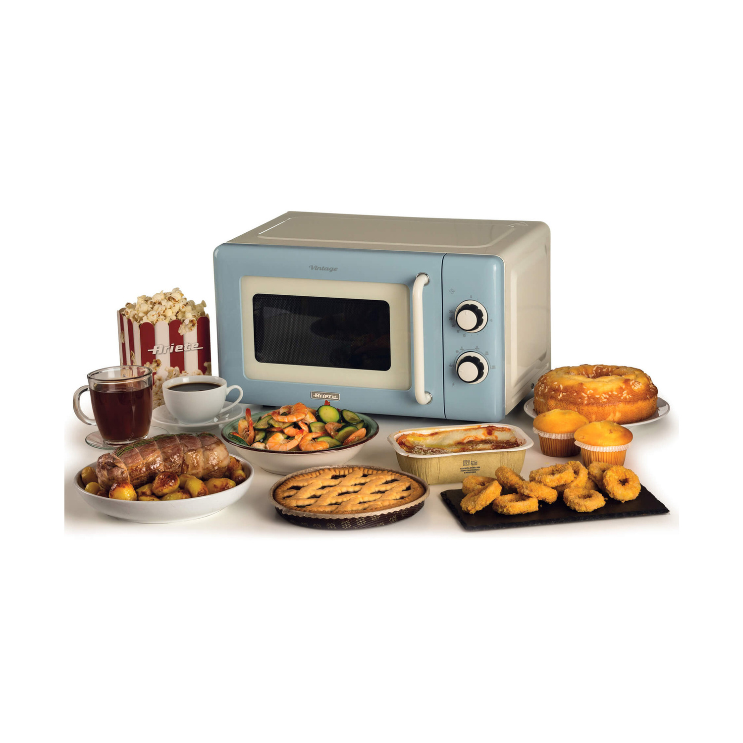Un forno a microonde vintage azzurro è circondato da vari piatti preparati e snack su sfondo bianco.