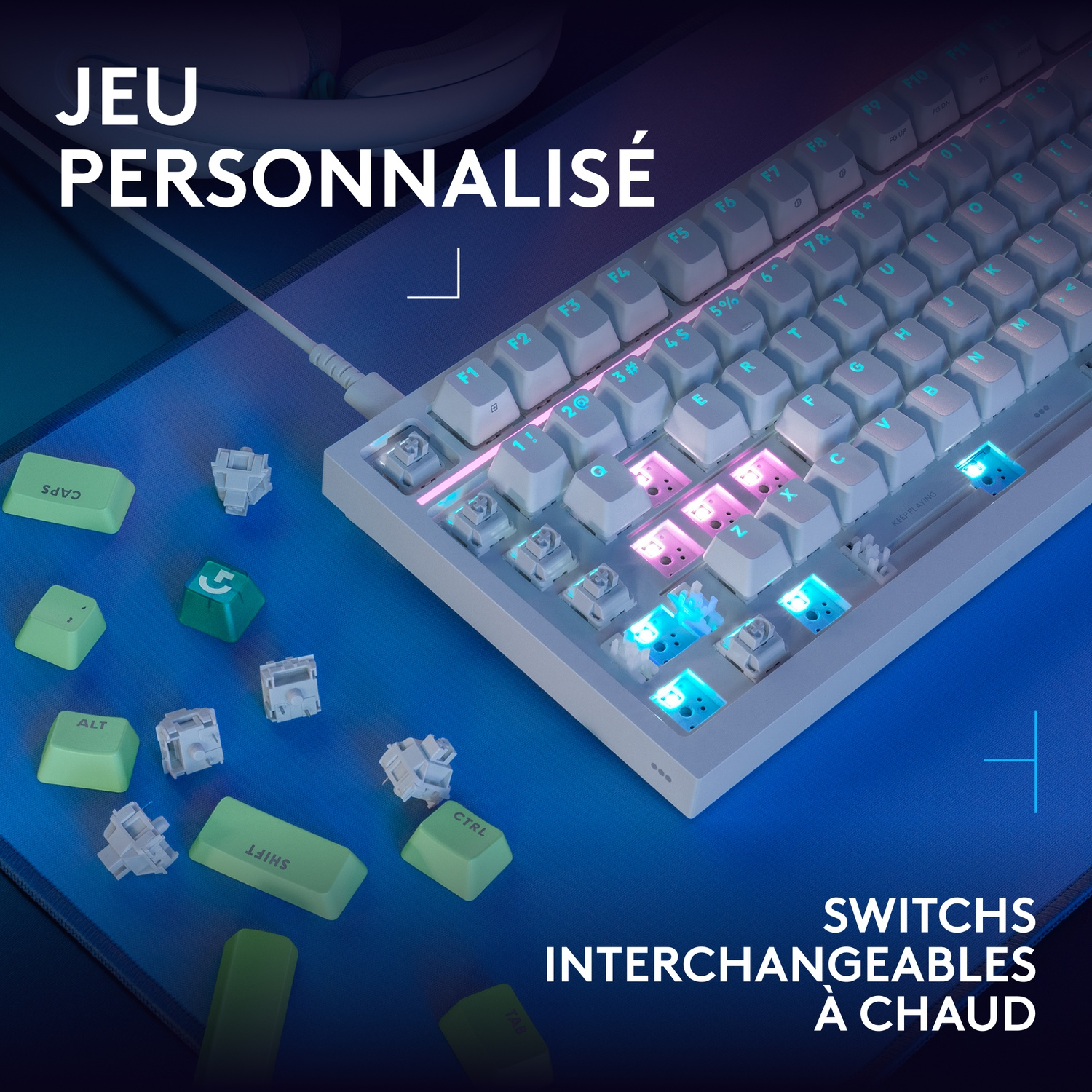 Un clavier personnalisé avec des interrupteurs interchangeables et des touches colorées sur un tapis de bureau bleu.