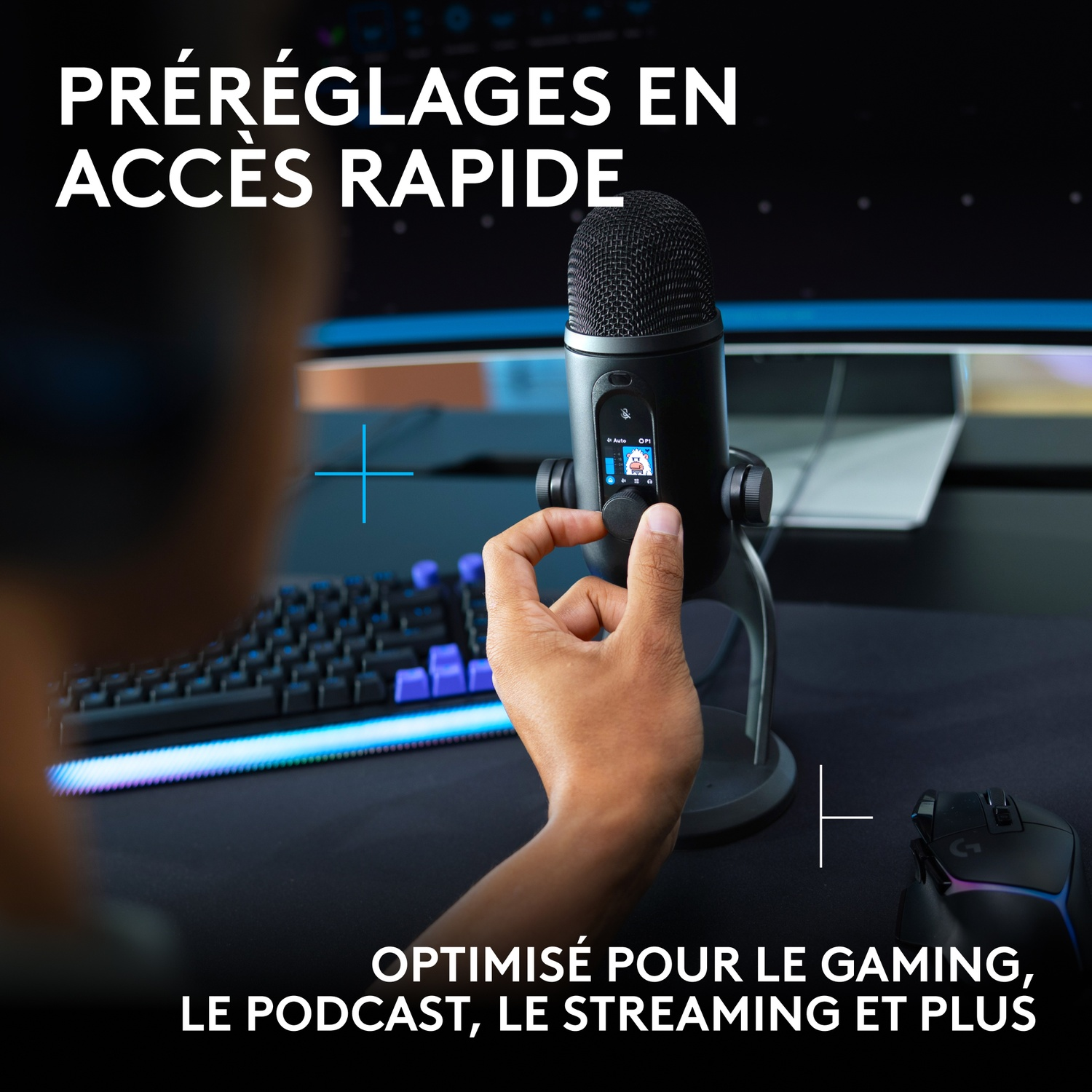 Une personne ajuste un microphone de jeu noir avec écran LCD sur un bureau.