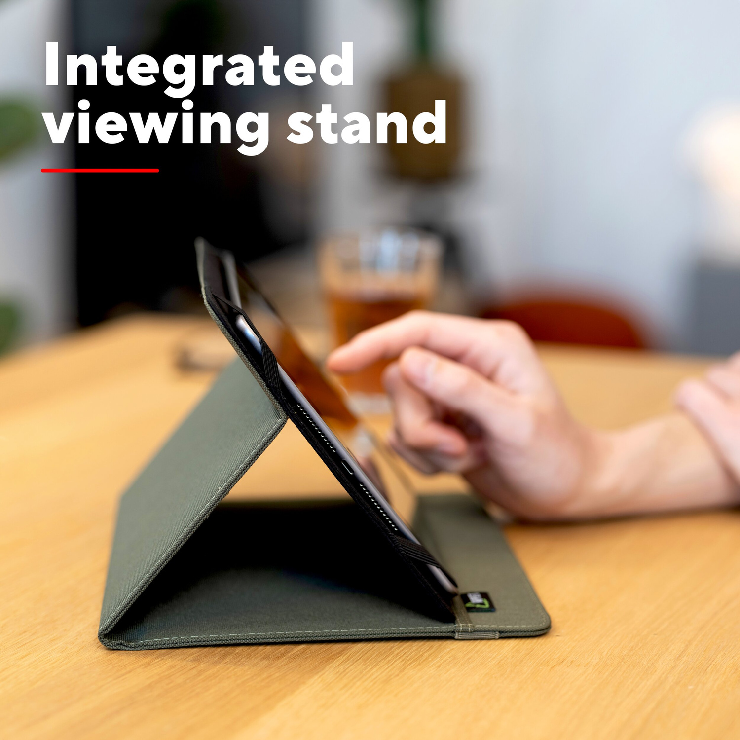 Un tablet in una custodia verde poggia su un tavolo di legno mentre una mano tocca lo schermo.