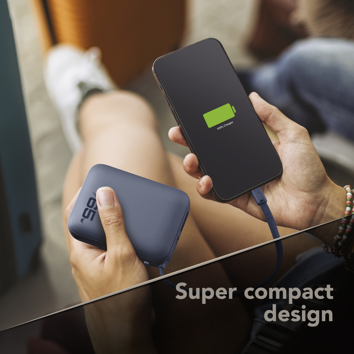 Una persona tiene in mano un power bank grigio e carica uno smartphone.