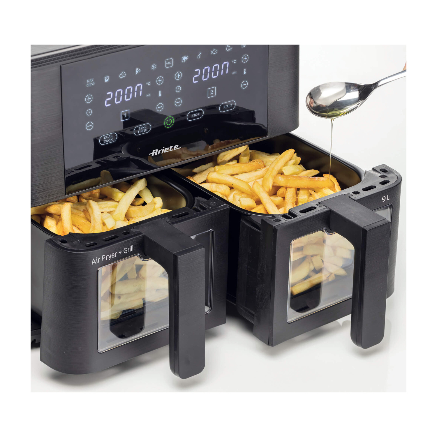 L'olio viene versato da un cucchiaio nel cassetto aperto di una friggitrice ad aria doppia Ariete nera con patatine fritte.