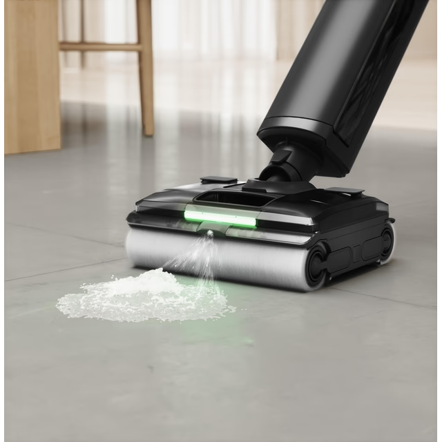 Un aspirateur eau et poussière noir pulvérise de l'eau sur un sol sale, avec des meubles en bois en arrière-plan.